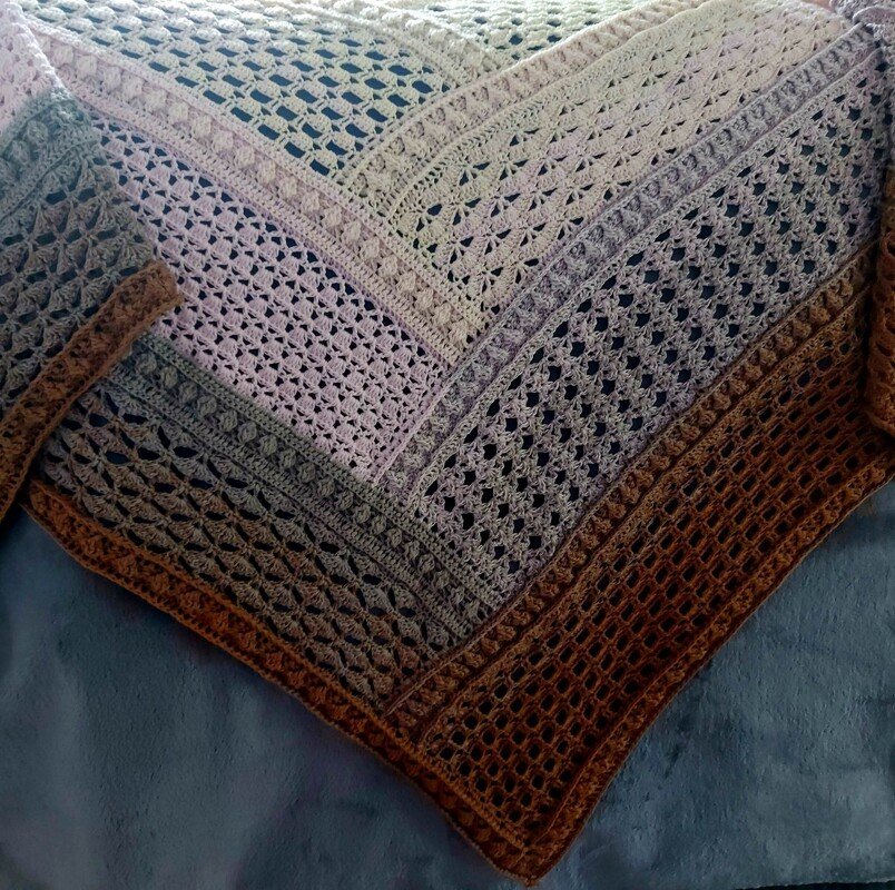 Muted gradient triangular crochet shawl with textured openwork bands and wide border