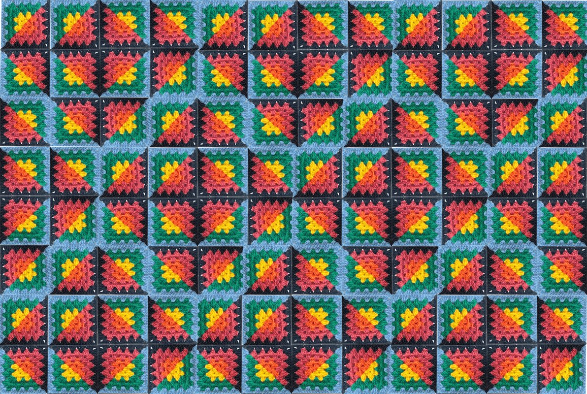 Nahaufnahme einer bunten gehäkelten Decke aus Granny-Quadraten mit diagonalen Farbflächen