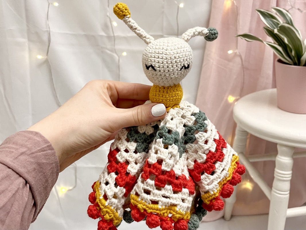 Gehäkeltes Schmusetuch mit Bommelkante und Amigurumi-Kopf, handgehalten
