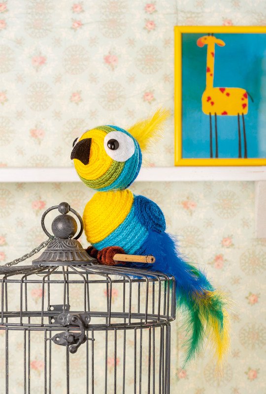 Bunter Garnpapagei mit Federschwanz auf Metall-Vogelkäfig