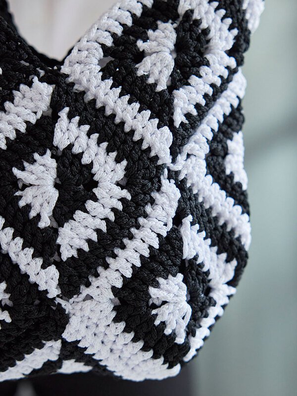 Nahaufnahme eines gehäkelten schwarz-weißen Shoppers aus Granny-Squares mit sichtbarer Maschenstruktur