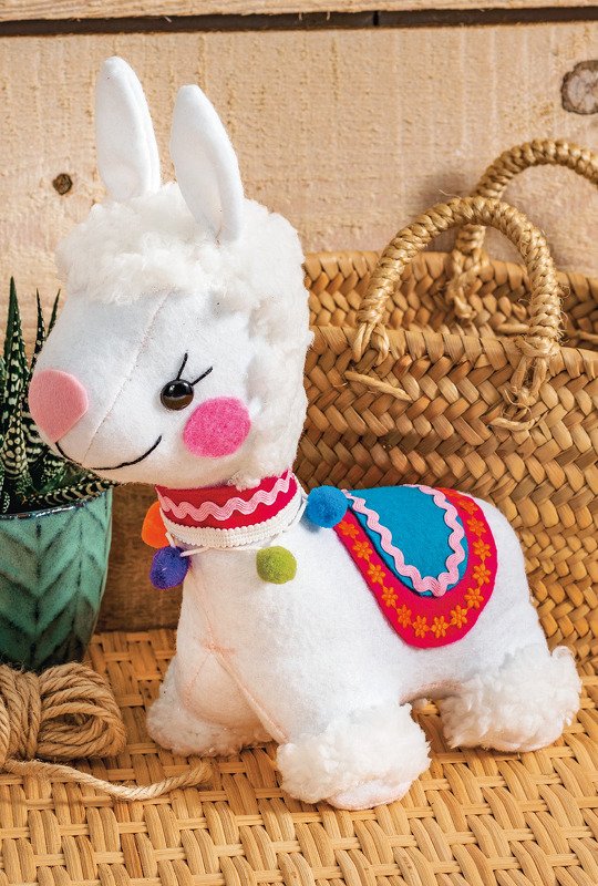 Detailaufnahme eines weißen Lama-Kuscheltieres mit sichtbaren Nähten, Filz-Nase und buntem Sattel