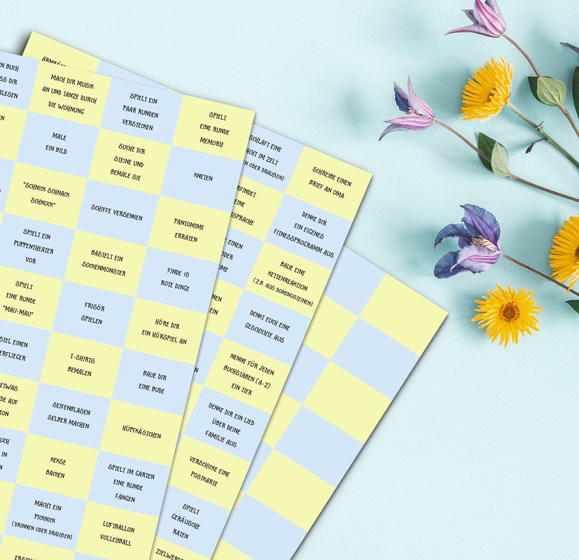 Gedruckte Aktivitätsblätter mit gelben und blauen Kästchen voller Kurzaufgaben, auf hellem Hintergrund liegend
