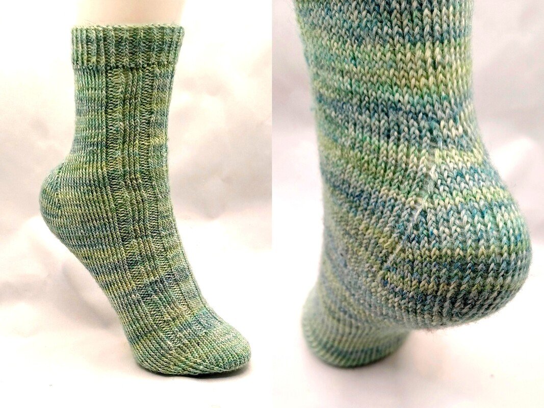 Grün-blau melierte handgestrickte Socke auf Fußmodell, Seiten- und Fersendetail sichtbar.