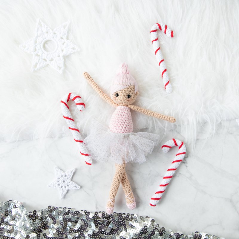 Gehäkelte Amigurumi‑Ballerina in rosa Tüll‑Tutu mit gehäkelten Zuckerstangen und Sternen auf hellem Hintergrund