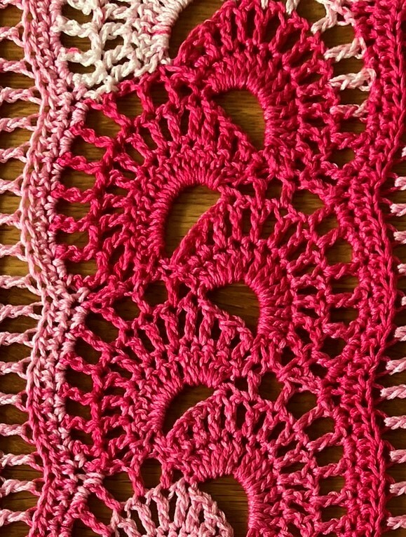 Häkelstoff in Hell- bis Dunkelrosa mit sich wiederholenden Fächermotiven