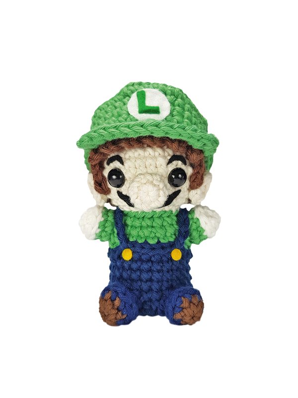 Gehäkelte Amigurumi-Figur mit grüner Mütze, blauer Latzhose und schwarzen Augen