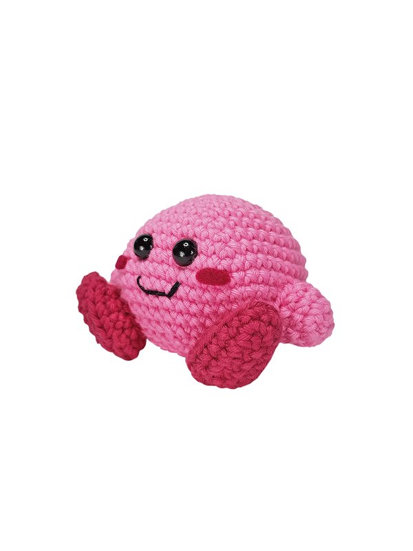 Rundes rosa Amigurumi mit schwarzen glänzenden Augen und kleinen Füßchen vor weißem Hintergrund