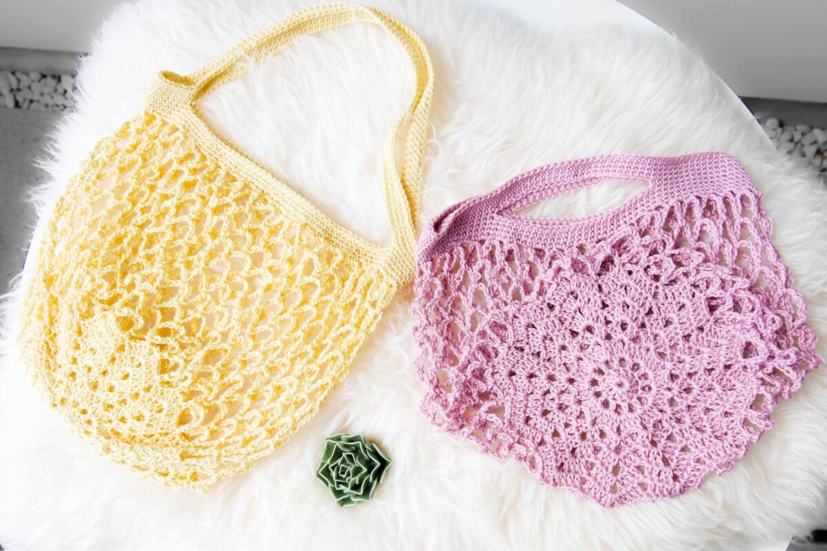 Gelbe und lila gehäkelte Netztaschen auf weißem Fell mit kleiner grüner Sukkulente
