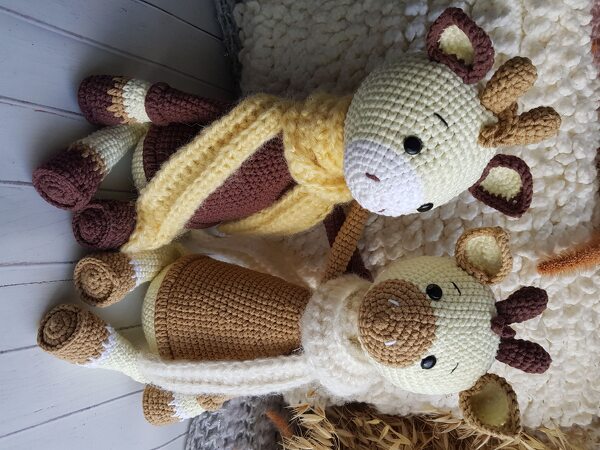Zwei gehäkelte Amigurumi-Giraffen, eine mit gelbem Schal und eine mit cremefarbenem Schal.