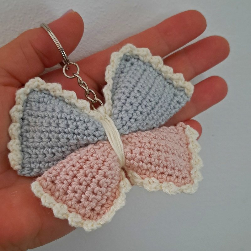 two-tone pastel crochet butterfly keyring with cream scalloped edge held in a hand