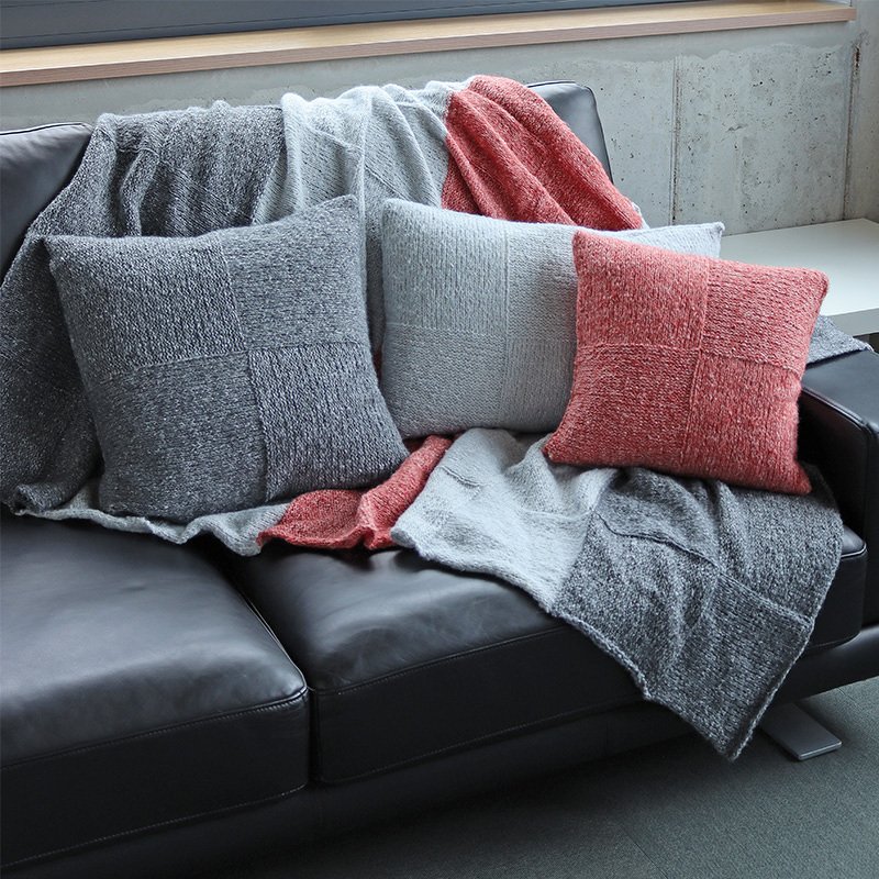 Quadrat-Strickmuster auf Decke und Kissen in Grau und Rosé