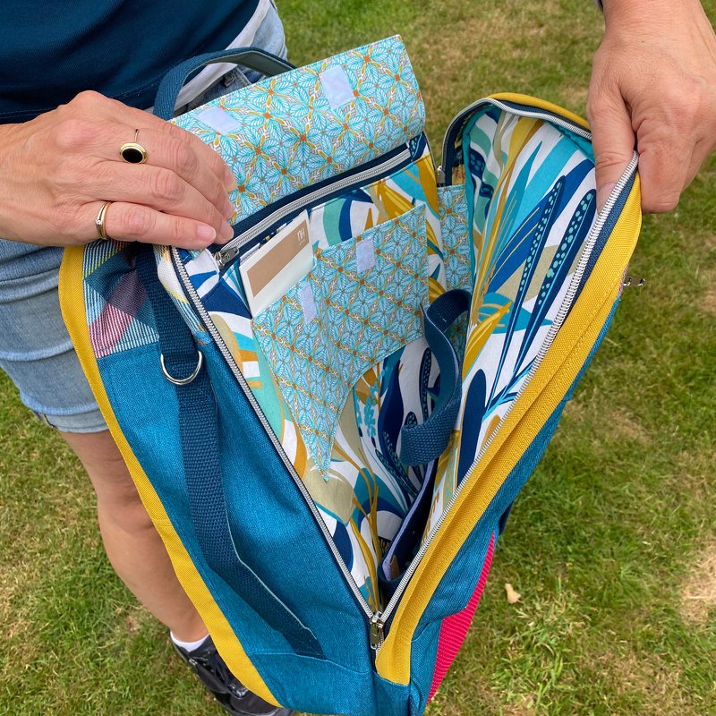 Offene Nähtasche aus petrolfarbenem Stoff mit gelben Randdetails, gemustertem Innenfutter, Reißverschluss und mehreren Innenfächern