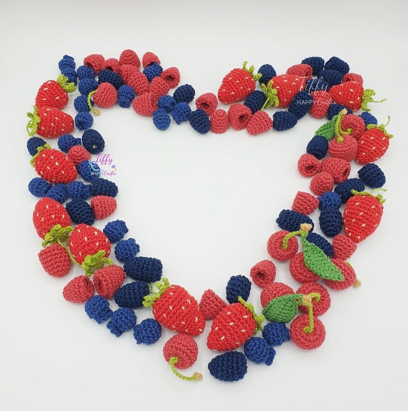 Crocheted play food berries (strawberries, blueberries, raspberries) arranged in a heart shape for children