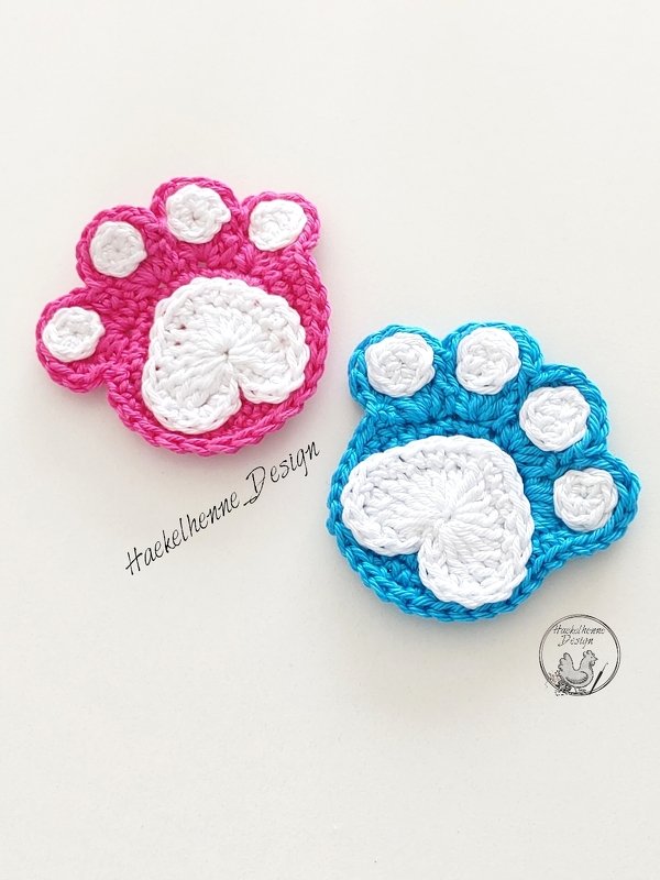 Zwei kompakte, schnell gehäkelte Pfotenapplikationen in Pink und Blau mit weißen Ballen