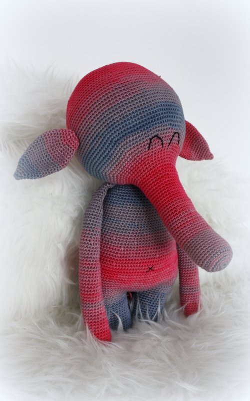 Gehäkelter Amigurumi-Elefant in rot-blau-grauem Verlaufsgarn auf flauschigem Hintergrund