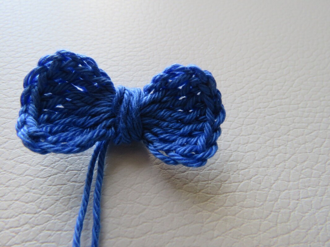 kleine gehäkelte blaue Schleife aus Garn auf hellem Untergrund
