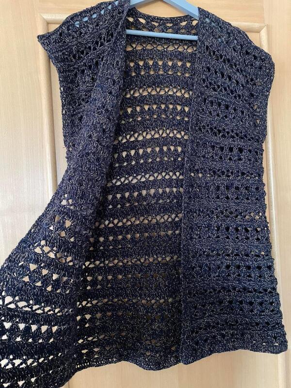 Dunkle gehäkelte ärmellose Weste mit offenem Vorderteil an einem Kleiderbügel