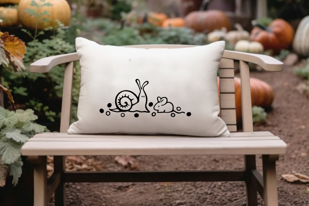 Cremefarbenes Kissen mit schwarzem Schnecken- und Maus-Plott auf Holzstuhl