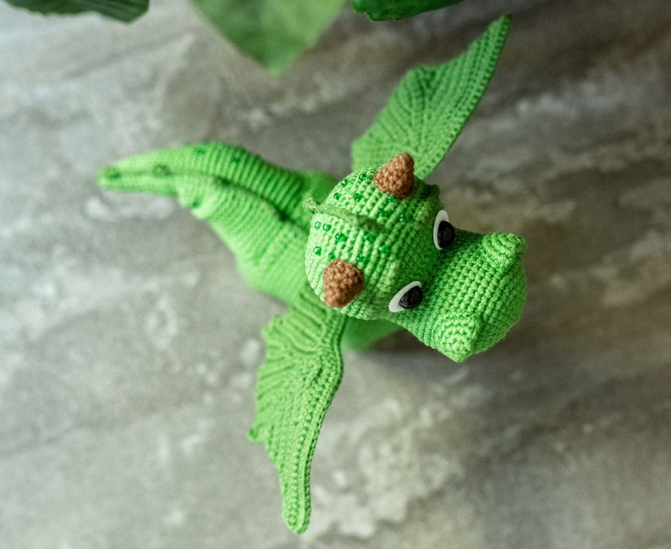 Close-up of stitch detail on wings and head of a green crocheted dragon amigurumi