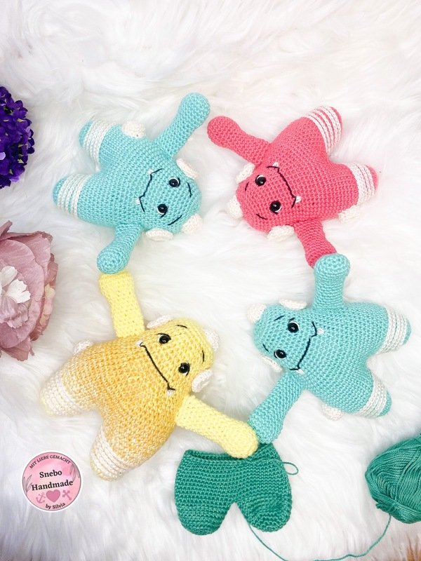 Gehäkelte Amigurumi-Figuren in Pastellfarben und ein halbfertiges Häkelstück auf weichem Untergrund