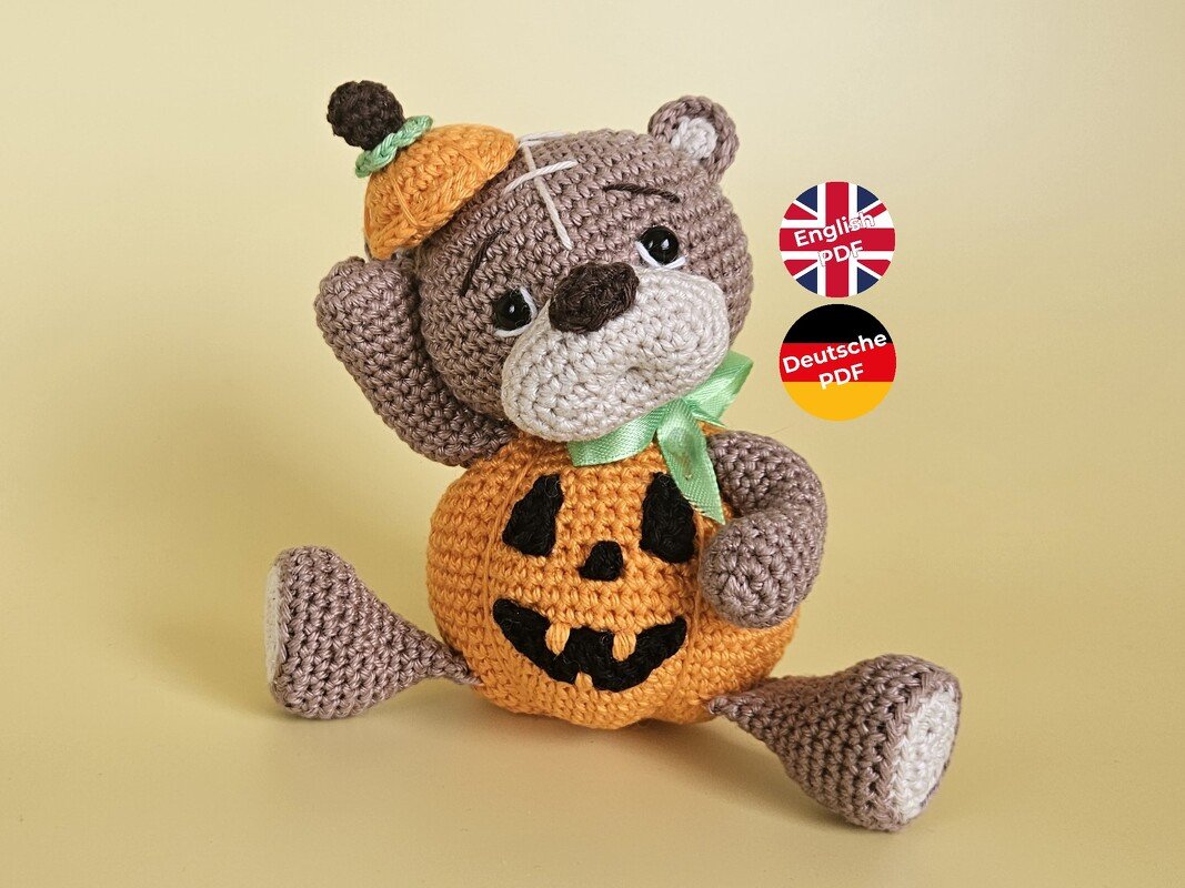 Sitzender gehäkelter Teddybär mit orangefarbenem Kürbis‑Körper und kleinem Kürbishut