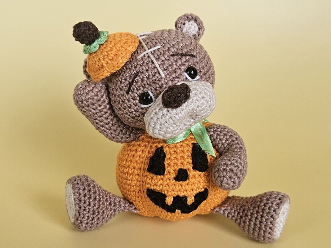Gehäkelter brauner Teddy mit orangefarbener Kürbis-Weste und kleinem Kürbis-Hütchen