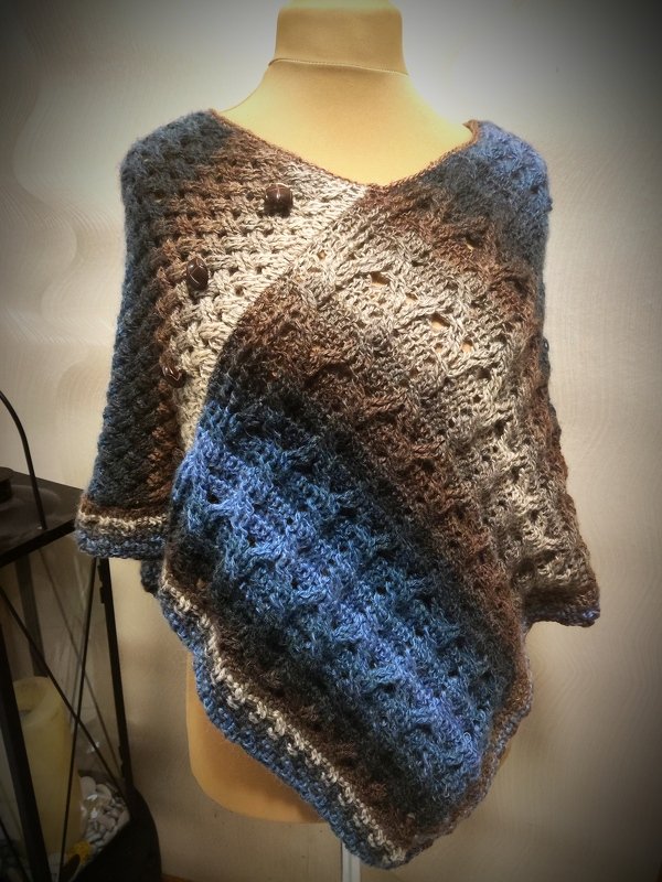 Gehäkelter Poncho in Blau, Braun und Grau mit Lochmuster auf Schaufensterpuppe