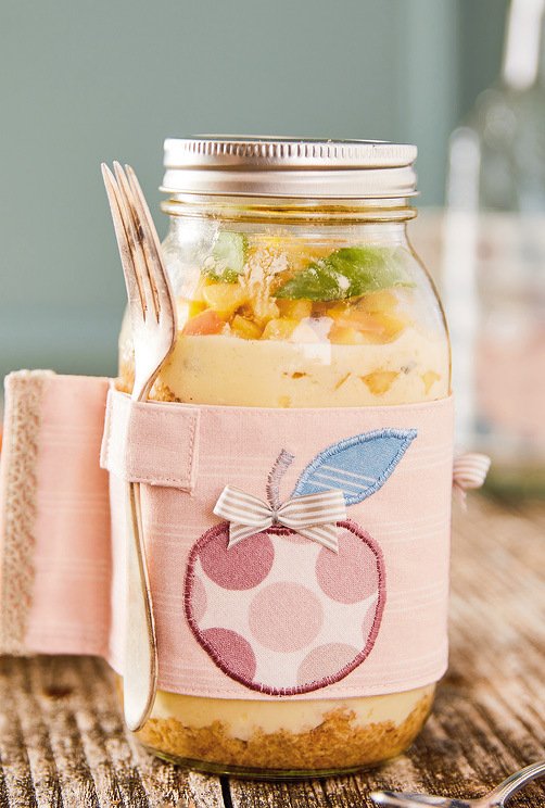 Nahaufnahme: Einmachglas mit rosa genähter Hülle, Apfel‑Applikation und Gabel