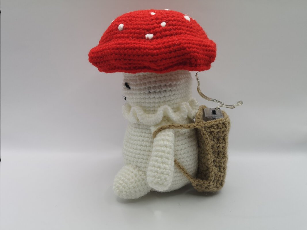Gehäkelter Fliegenpilz-Amigurumi mit rotem Hut, Rüschenkragen und Rucksack mit Batteriefach