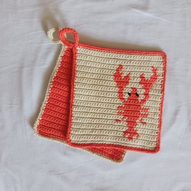 Zwei doppellagige gehäkelte Topflappen in Koralle und Creme mit Aufhängeschlaufen, einer mit Hummer-Motiv