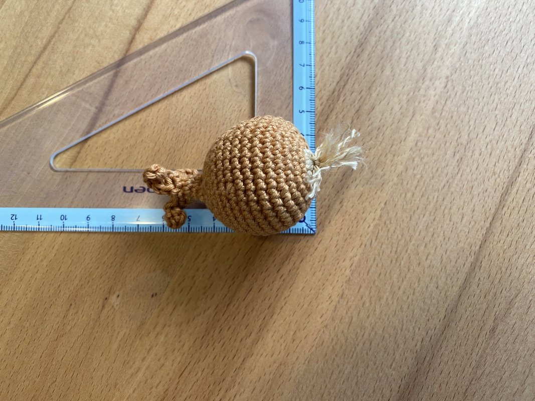 Gehäkelte braune Zwiebel auf Holz neben Lineal