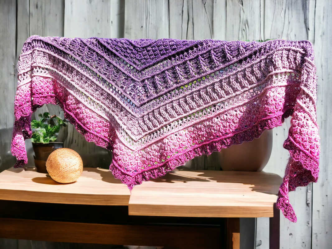Crochet triangle shawl featuring lace rows, textured bands, and a scalloped border in a purple-to-pink gradient.