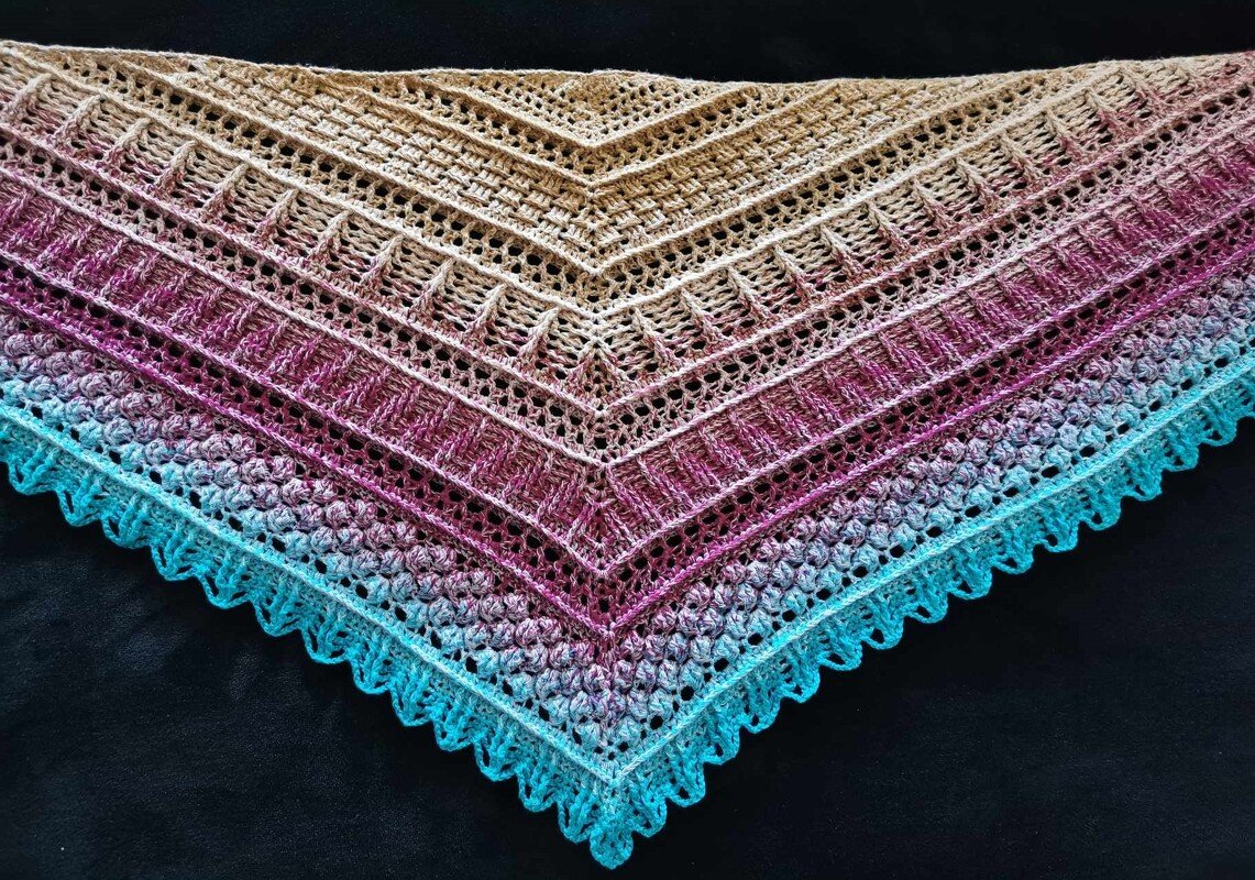 Close-up of triangle crochet shawl in beige-to-turquoise gradient showing openwork rows, ribbed bands and scalloped edge.