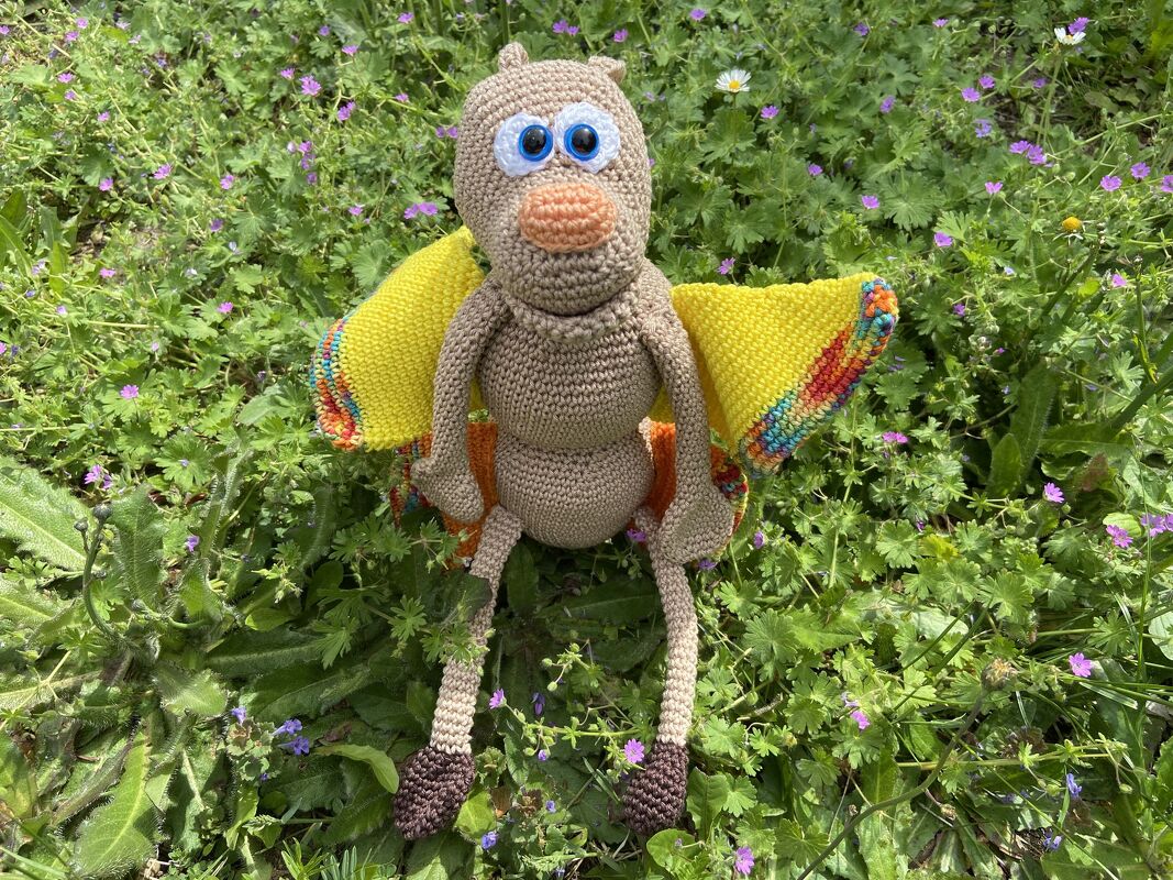 Gehäkeltes Schmetterling-Amigurumi mit gelben Flügeln auf Gras