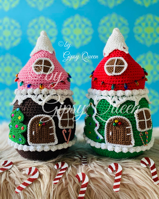 Zwei gehäkelte Lebkuchenhäuschen mit rosa und roten Dächern, braunen und grünen Körpern, verziert mit weißen Details und Zuckerstangen.