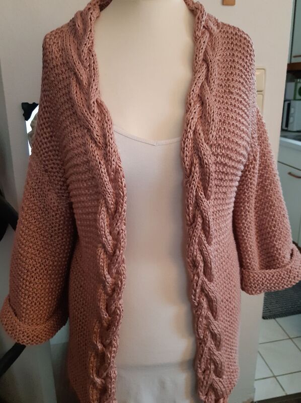 Hellrosa Damen-Strickjacke mit Zopfmuster an der Vorderkante und hochgekrempelten Ärmeln auf einer Schaufensterpuppe