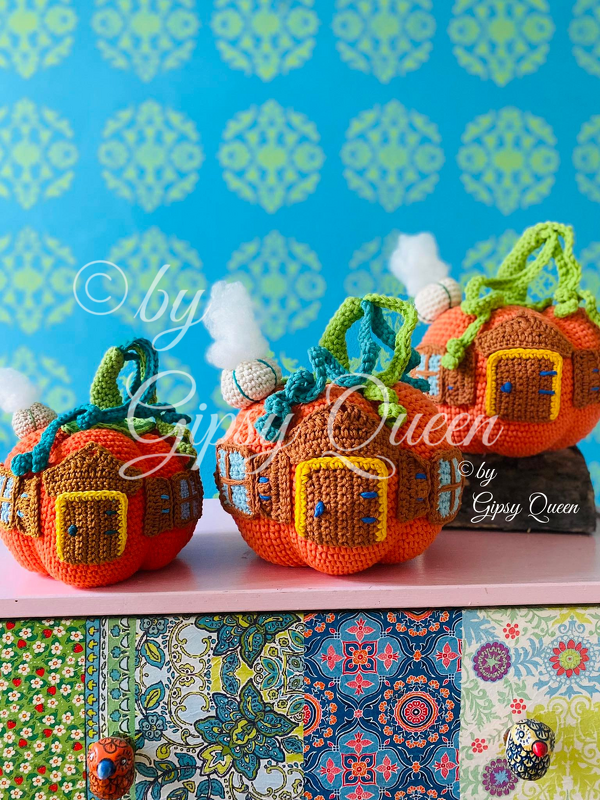 Drei handgehäkelte orange Kürbishäuschen mit liebevollen Details.