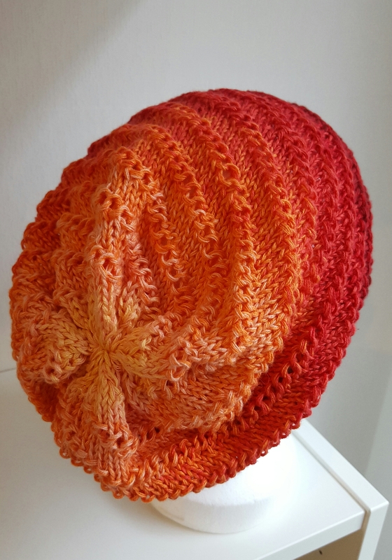 locker gestrickte Beanie mit orange-rotem Farbverlauf auf weißer Schaufensterkopfattrappe