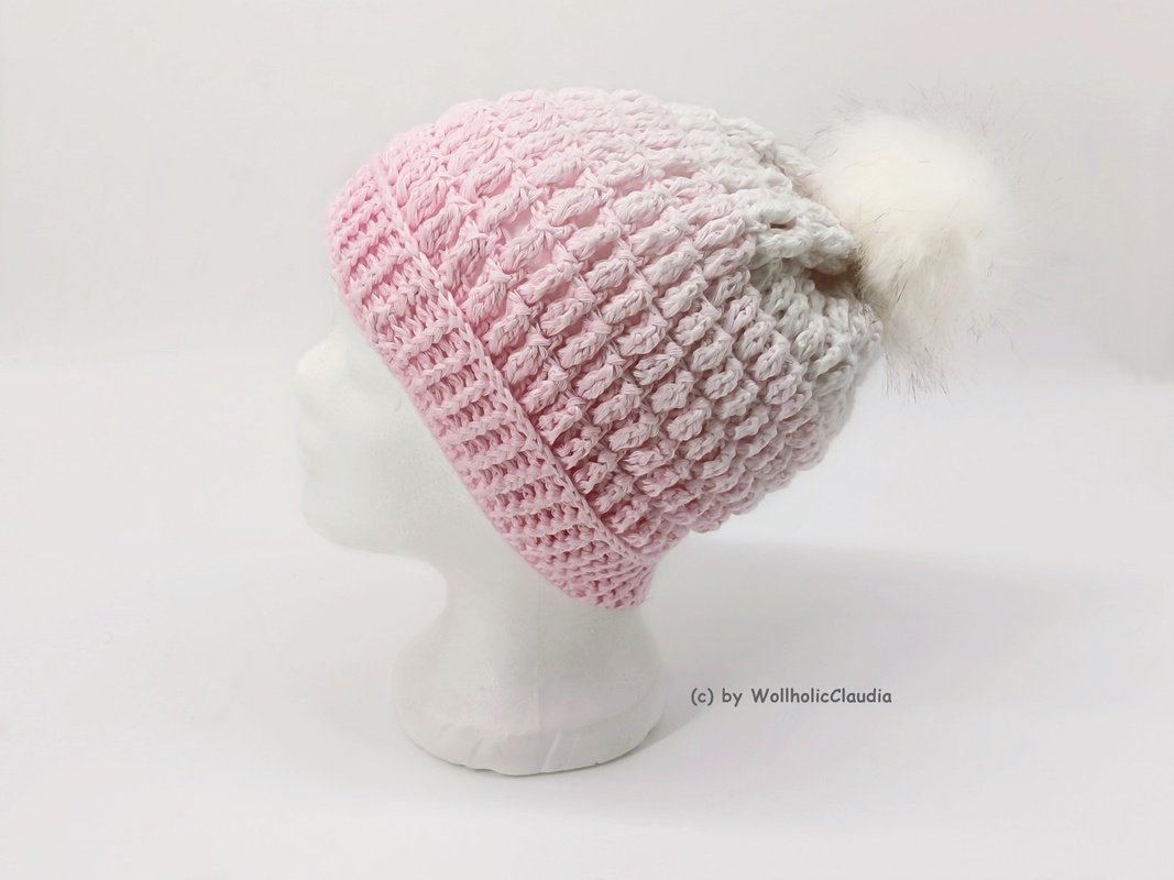 Rosa gehäkelte Beanie mit Strukturmuster und weißem Bommel auf weißer Schaufensterbüste