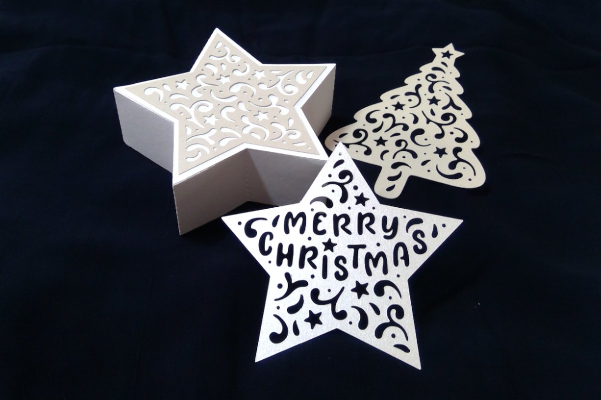 Sternbox, Stern mit ",Merry Christmas", und ornamentaler Tannenbaum aus hellem Papier auf dunklem Hintergrund