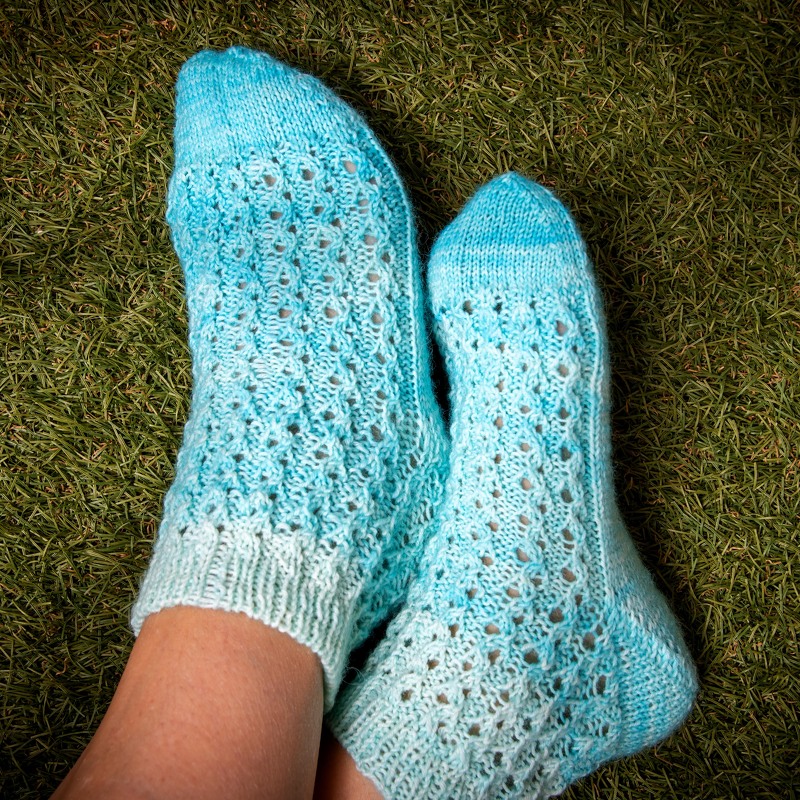 Helltürkise gestrickte Knöchelsocken mit Lochmuster auf Gras