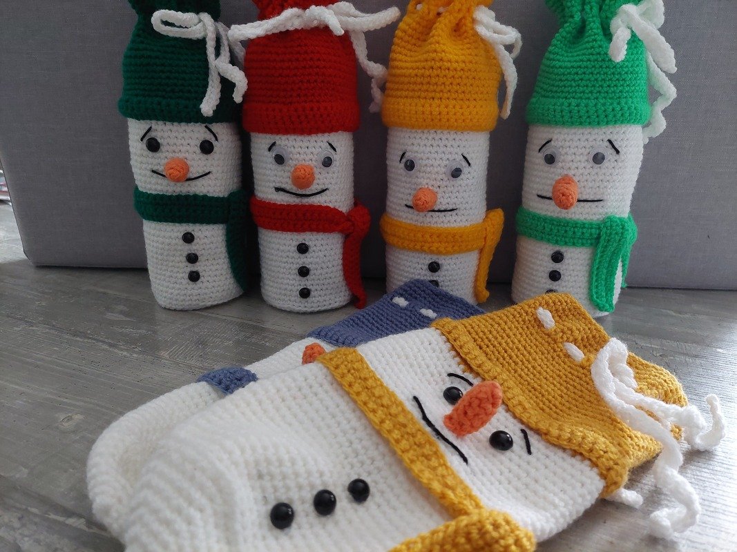 Gehäkelte Schnemann‑Flaschenhüllen in verschiedenen Farben mit Mützen und Schals