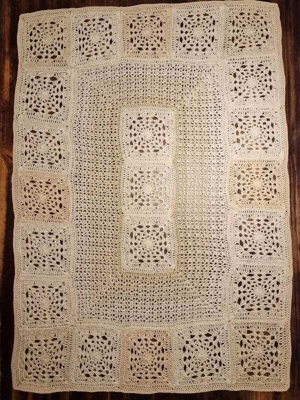 Naturfarbener gehäkelter Tischläufer aus verbundenen Granny-Quadraten auf dunklem Holz