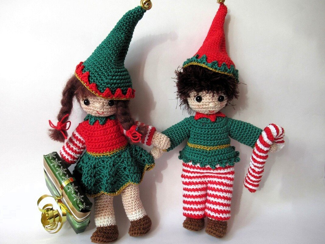Zwei gehäkelte Amigurumi-Wichtel zu Weihnachten mit Geschenk und Zuckerstange vor weißem Hintergrund