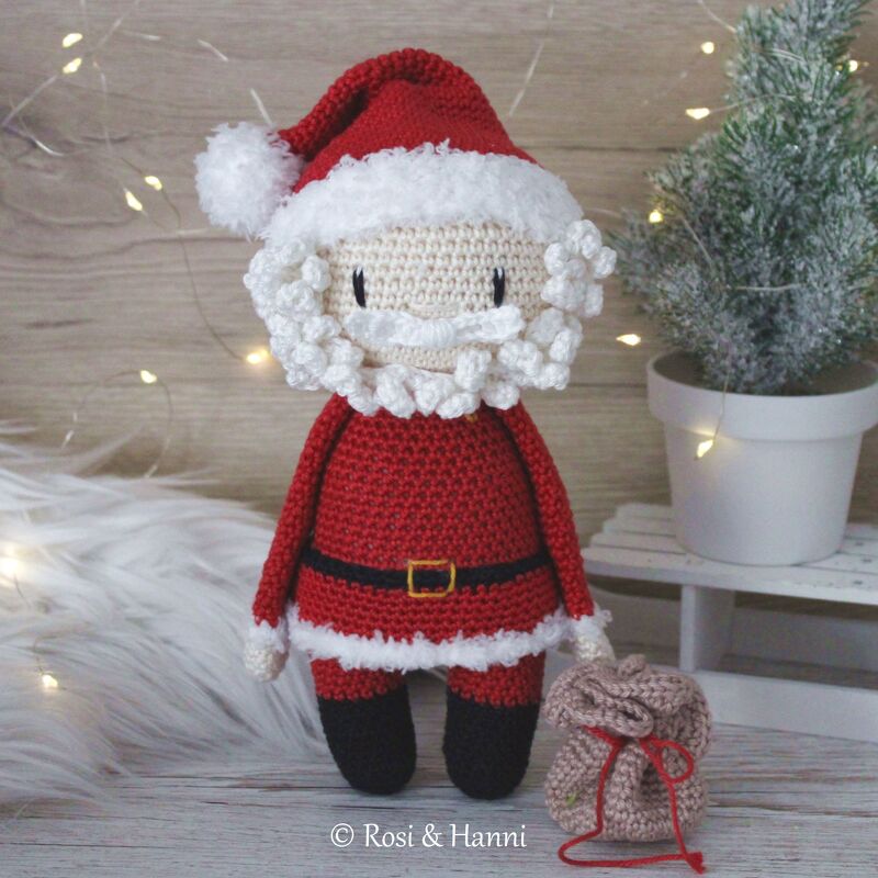 Gehäkelter Amigurumi-Weihnachtsmann in rotem Anzug mit weißem Bart und kleinem Sack
