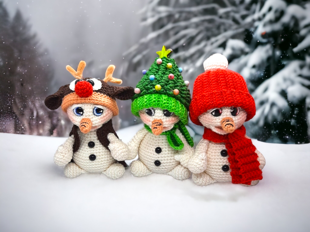 Drei gehäkelte Amigurumi‑Schneemänner: Rentier, Weihnachtsbaum, Schneemann mit roter Mütze