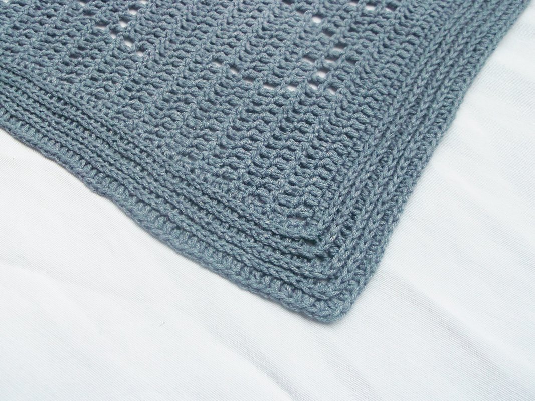 Close-up of dusty blue crochet baby blanket border and corner stitches