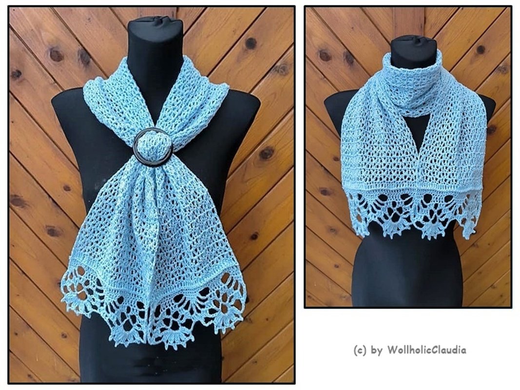 Zwei Ansichten eines hellblauen gehäkelten Schals auf einer schwarzen Schneiderpuppe vor Holzpaneelen. Feines Lochmuster und dekorative Spitzenborte sichtbar.
