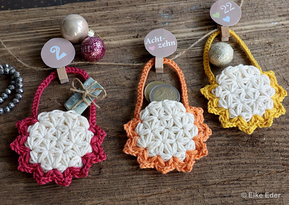 Close-up of three flower-style crocheted mini pouches with colored scalloped edges, suitable for an advent calendar.